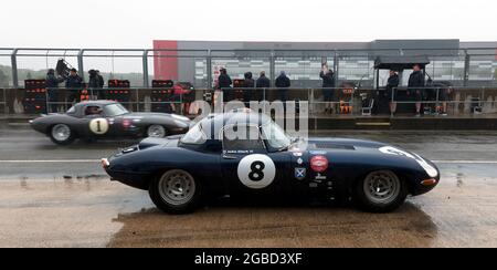 Miles Griffiths E-Type s'arrête à la fosse, tandis que la voiture de Martin et Alex Bundles passe à travers la voie de la fosse, pendant le 60e anniversaire du défi E-Type Banque D'Images