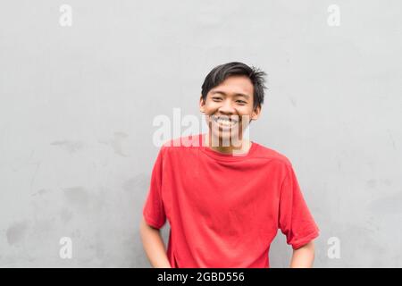 Gros plan d'un jeune homme dans un T-shirt rouge riant. Banque D'Images