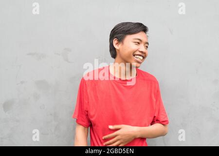 Gros plan d'un jeune homme dans un T-shirt rouge riant. Banque D'Images