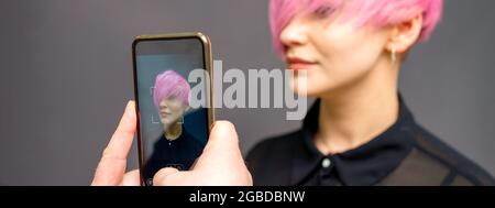 Les mains de coiffeur d'homme prenant la photo sur le smartphone de son client court hairstyle rose Banque D'Images