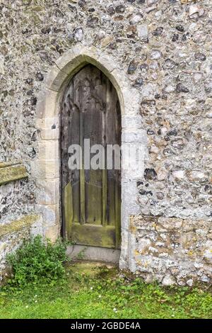 Une ancienne église Oak Norfolk voûtée porte latérale dans un mur de silex Banque D'Images