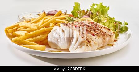 Poisson de pollack cuit appétissant servi sur une assiette avec des frites croustillantes et des feuilles de salade sur fond blanc Banque D'Images