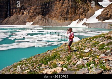 Randonneur se faisant une pause pour regarder la glace flottant dans Upper Grinnell Lake, de nombreux glaciers, Glacier National Park, Montana Banque D'Images