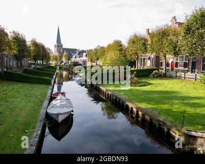 Jardins au bord de l'eau sur le canal Eegracht et l'église Maurice dans la ville d'IJlst, Frise, pays-Bas Banque D'Images