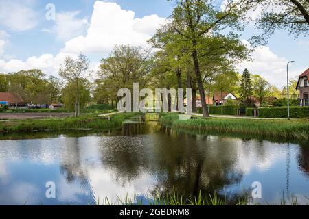 Canal avec eau entouré d'herbe, de verdure, de nature et de maisons sur une campagne rurale néerlandaise pittoresque et calme à Grientsveen, pays-Bas sur a s. Banque D'Images