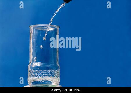 Eau distillée s'écoulant dans un récipient en verre Banque D'Images