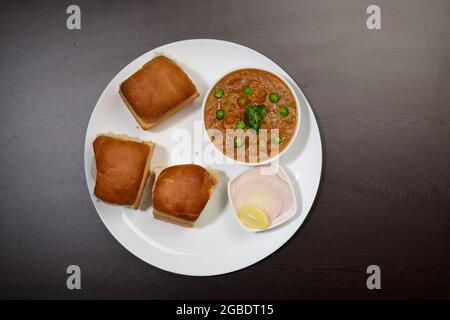 PAV Bhaji cuisine indienne épicée avec pain en gros plan dans un bol sur la table. Vue horizontale du dessus Banque D'Images