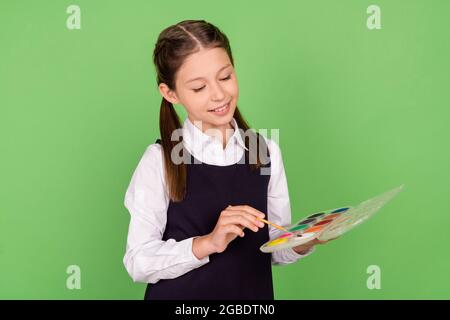 Photo portrait écolière maintien de la palette de couleurs avec pinceau isolé pastel couleur vert fond Banque D'Images