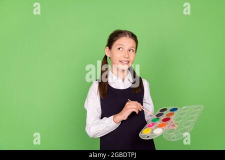 Photo portrait écolière maintien de la palette de couleurs avec pinceau aspect Copyspace isolé pastel couleur vert arrière-plan Banque D'Images