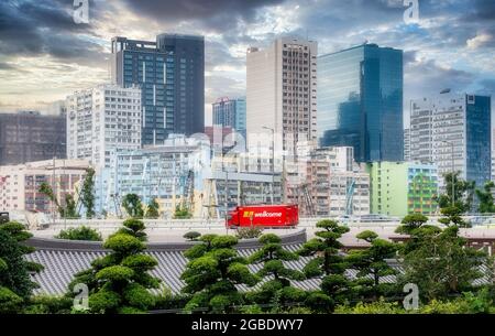 HONG KONG, HONG KONG - 24 juillet 2018 : une vue de Hong Kong depuis les jardins de Ban Lean - montrant des pins verts en premier plan... la vue inclut un camion rouge cr Banque D'Images