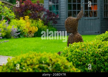 Sculpture de saule caractéristique ornementale de fille (boîte clippée, pelouse, abri d'été, raindrops) - jardin privé paysagé, Yorkshire, Angleterre, Royaume-Uni. Banque D'Images