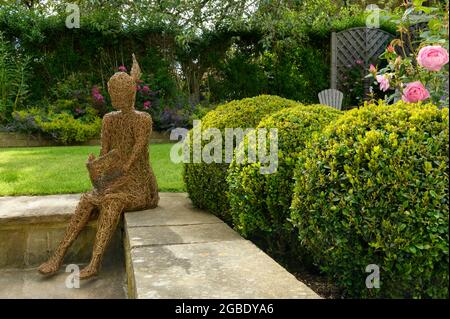 Sculpture (élément ornemental) dans un magnifique jardin paysagé coloré (plantes et arbustes à fleurs, roses, balles, pelouse) - Yorkshire England UK Banque D'Images