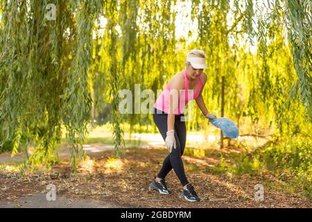 une jeune femme se porte volontaire pour ramasser des déchets dans le parc. Concept de protection de l'environnement Banque D'Images