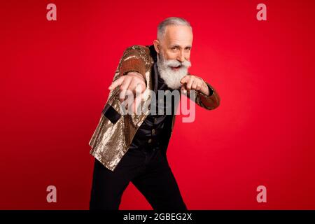 Photo d'une belle barbe grise homme illusionniste d'âge indique que vous portez un costume d'or isolé sur fond rouge Banque D'Images