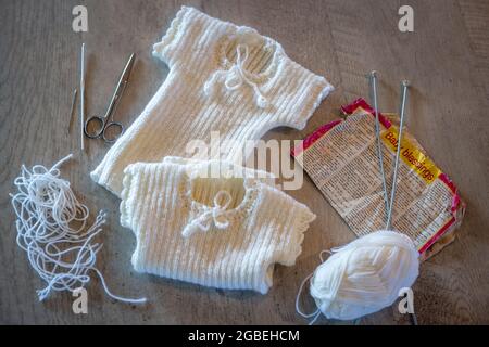 Les maillots en laine de bébé merino sont tricotés à la main avec des bordures en crochet en préparation pour un nouveau bébé Banque D'Images