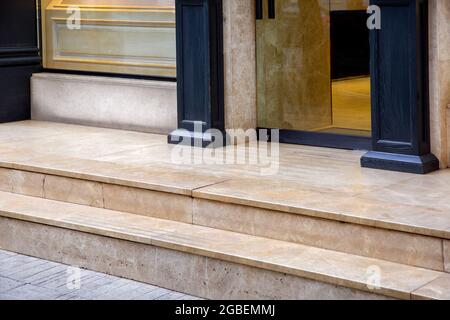 seuil en marbre clair avec marches à l'entrée de la porte vitrée d'un hôtel cher avec des colonnes en bois décoratives noires sur la façade en gros plan Banque D'Images