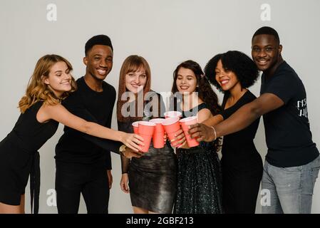 Taille jusqu'à six amis ayant le plaisir et boire de l'alcool pendant la fête du nouvel an, isolé sur fond blanc. Un groupe d'amis joyeux de différents Banque D'Images