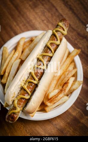 hot dog allemand à la saucisse avec frites et moutarde sur fond de table en bois Banque D'Images