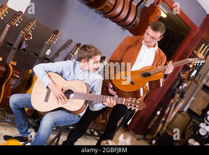 Garçon et père choisissant la guitare acoustique Banque D'Images