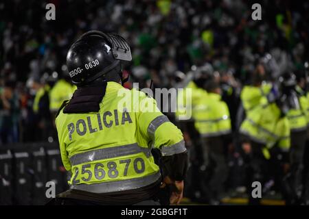 La police colombienne maintient une tribune de partisans de l'Atletico Nacional alors que les partisans de l'Independiente Santa Fe inondent le terrain du stade Nemesio Camacho el Campin après que les partisans de l'équipe Atletico Nacional ont violemment attaqué les partisans de Santa Fe dans une tribune provoquant la suspension du premier match de football avec Fans à Bogota, Colombie, le 3 août 2021. Banque D'Images