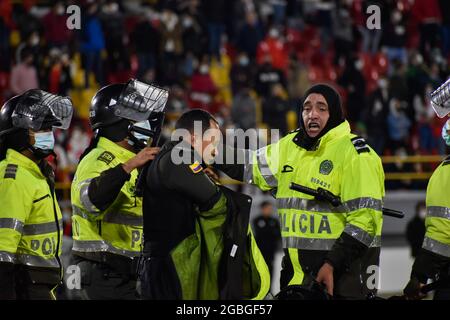 Un policier blessé lors d'affrontements est dédaigné par d'autres policiers à l'extérieur du terrain alors que les partisans de l'Independiente Santa Fe inondent le champ du stade Nemesio Camacho el Campin après que les partisans de l'équipe Atletico Nacional ont violemment attaqué les partisans de Santa Fe dans une tribune causant la suspension du Premier match de football avec des fans à Bogota, Colombie, le 3 août 2021. Banque D'Images