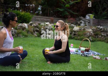 deux jeunes femmes dans leur jardin faisant du yoga et puis buvant des boissons détox Banque D'Images