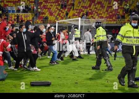 La police colombienne tente de retenir les partisans de l'Independiente Santa Fe sur le terrain tandis que les partisans de l'Independiente Santa Fe inondent le champ du stade Nemesio Camacho el Campin après que les partisans de l'équipe Atletico Nacional ont violemment attaqué les partisans de Santa Fe dans une tribune causant la suspension de la première Match de football avec des fans à Bogota, Colombie, le 3 août 2021. Banque D'Images