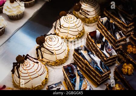 Gâteaux au chocolat pour le comptoir d'Halloween. Un ensemble de petits gâteaux et de friandises festifs décorés de saupoudrés et de bonbons dans une pâtisserie. Un arrière-plan de plusieurs Banque D'Images