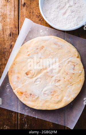 Pain plat, pita ou croûte de pizza sur une table de cuisine en bois Banque D'Images