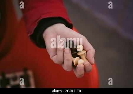 Gros plan sur des pièces d'échecs en main d'une femme méconnaissable. Une femme inconnue tient des figures d'échecs dans ses mains. Banque D'Images
