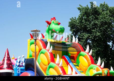 LIDA, BIÉLORUSSIE - 10 JUILLET 2021 : toboggan en caoutchouc coloré et trampoline pour les enfants dans le parc d'attractions en été. Banque D'Images