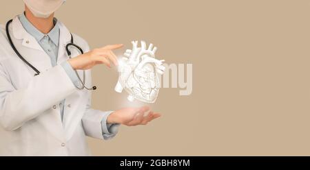 Femme médecin tenant un dessin volumétrique virtuel du cœur en main. Organe humain main, espace de copie sur le côté droit, couleur beige. Hôpital de soins de santé se Banque D'Images