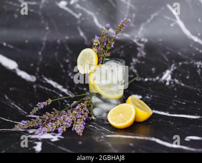 Limonade de lavande avec Citrus et glaçons isolés sur fond de marbre noir. Boisson rafraîchissante à la lavande en verre transparent. Banque D'Images
