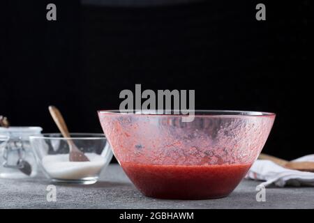Femme trainant de la confiture de fraises à travers un tamis, un concept de cuisine et de cuisine maison Banque D'Images