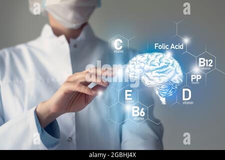 Nutriments essentiels pour la santé du cerveau, y compris la vitamine C, la vitamine B, l'acide folique, la vitamine PP. Portrait flou du médecin tenant le cerveau mis en évidence. Banque D'Images