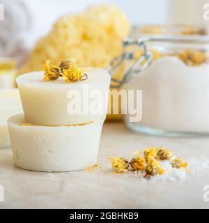 Barres rondes de savon faites à la main avec des herbes sèches fleurs de marigold. Produits de bain spa sel aromatique, débarbouillette naturelle sur table en marbre. Maison fait maison bricolage beauté Banque D'Images