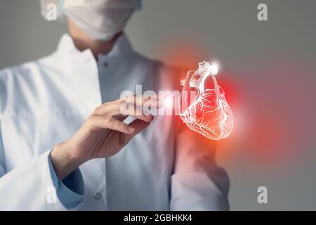 Femme médecin touchstone cœur virtuel en main. Photo floue, organe humain de la main, surligné en rouge comme symbole de la maladie. Service hospitalier de soins de santé Banque D'Images