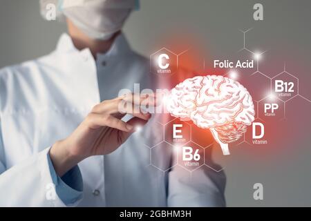 Nutriments essentiels pour la santé du cerveau, y compris la vitamine C, la vitamine B, l'acide folique, la vitamine PP. Portrait flou du médecin tenant le cerveau mis en évidence. Banque D'Images