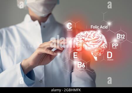 Nutriments essentiels pour la santé du cerveau, y compris la vitamine C, la vitamine B, l'acide folique, la vitamine PP. Portrait flou du médecin tenant le cerveau mis en évidence. Banque D'Images