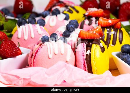 Macaron, magnifique Sweet food fait à la main, dessert avec des fraises fraîches et des bleuets décorés de chocolat, de délicats gâteaux jaunes et roses Banque D'Images