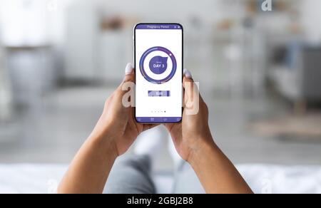 Jeune femme enceinte utilisant une application mobile pour la grossesse Banque D'Images
