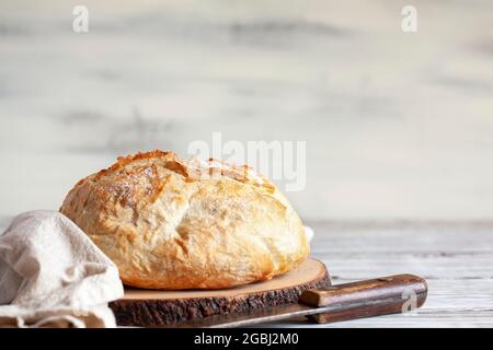 Pain artisanal frais fait maison sur une planche à découper avec torchon et couteau. Banque D'Images