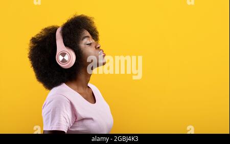 Méditation, relaxation et repos avec la musique. Femme afro-américaine calme dans un casque sans fil avec les yeux fermés Banque D'Images