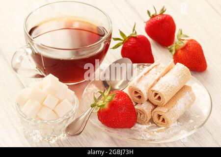 Dessert du matin avec thé, sucre et rouleaux de gaufres sucrées. Petit déjeuner lent avec baies fraîches et boisson chaude Banque D'Images