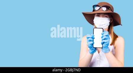 Une femme satisfaite porte un masque médical de protection pour ne pas infecter d'autres personnes, utilise le téléphone cellulaire pour surfer sur Internet pour trouver un remède. Banque D'Images