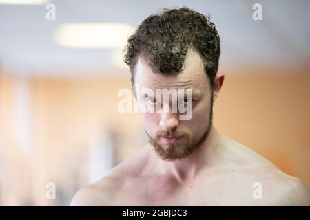 Un jeune homme avec une barbe regarde de sous ses sourcils. Banque D'Images