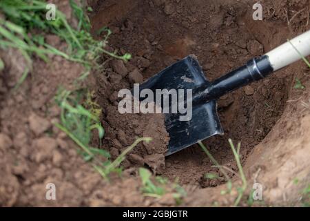 Une pelle en fer dans un trou dans le sol. Travaux de terrassement à main. Banque D'Images