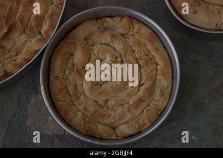 Tarte traditionnelle au fromage grec maison tortillé dans trois plats en fer avec filo, épinards, mizithra et feta. Banque D'Images