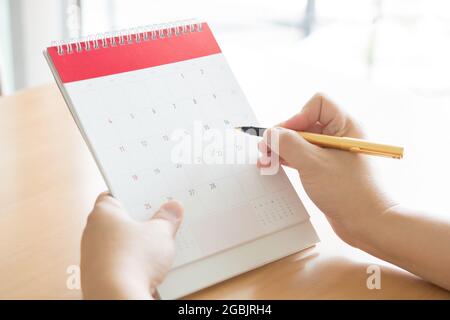 Main femme exerçant son calendrier et pointant sur elle par la plume Banque D'Images