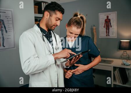 Race mixte deux infirmières parlent de l'horaire tout en lisant sur une tablette numérique Banque D'Images